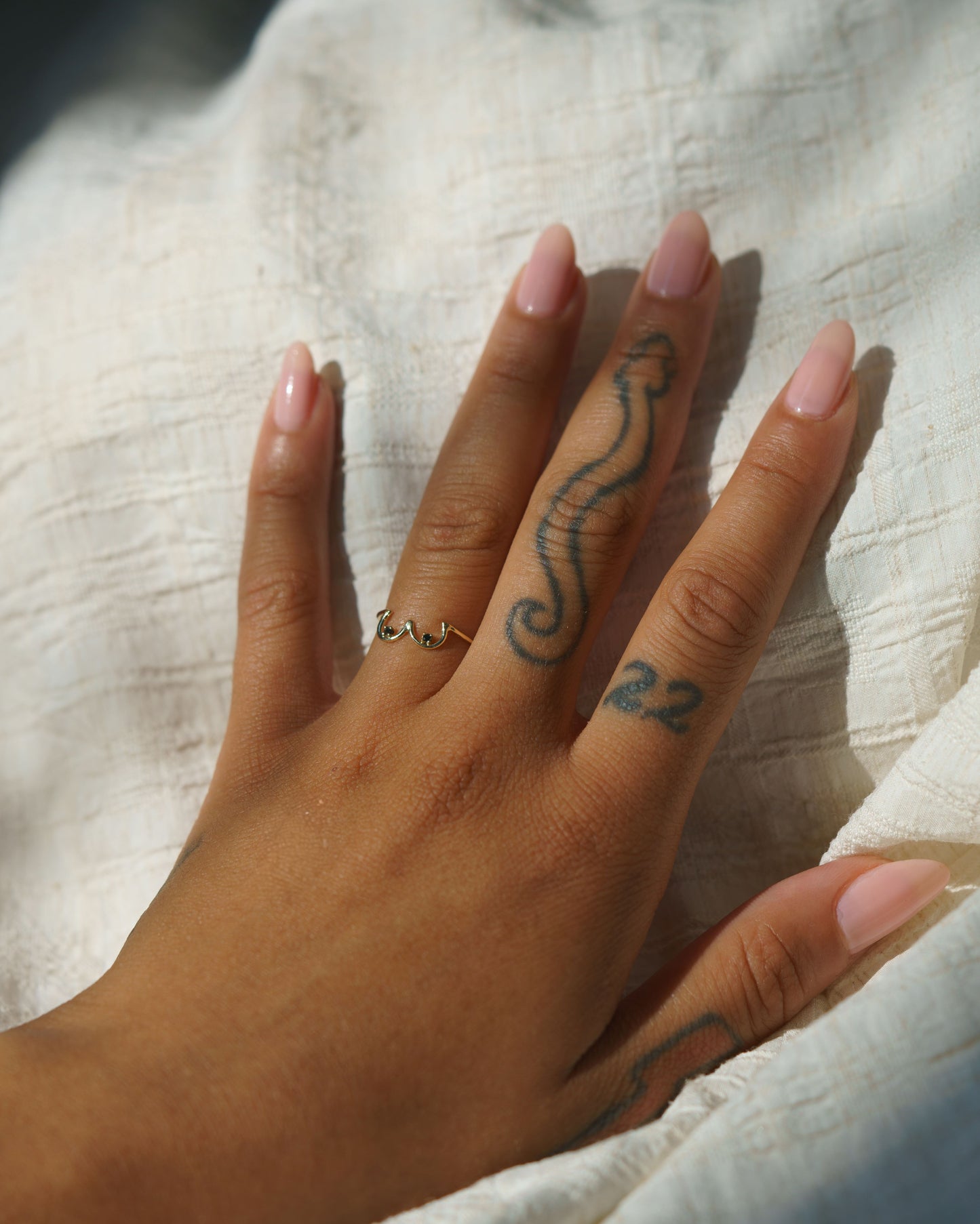 Black Diamond Boob Ring set in 14k yellow gold modeled on a hand