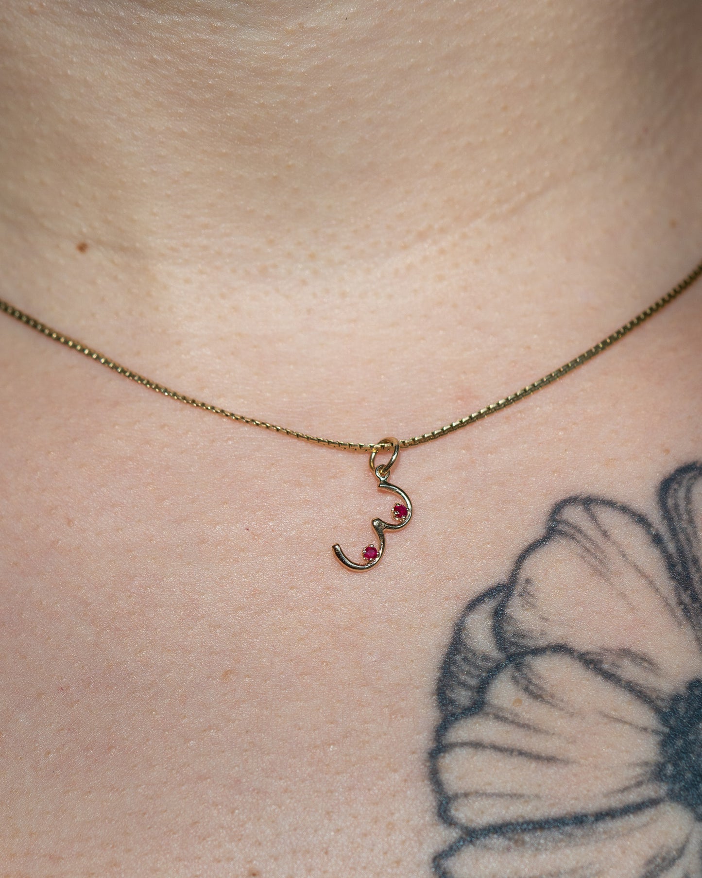 Boob Charm hanging on a necklace