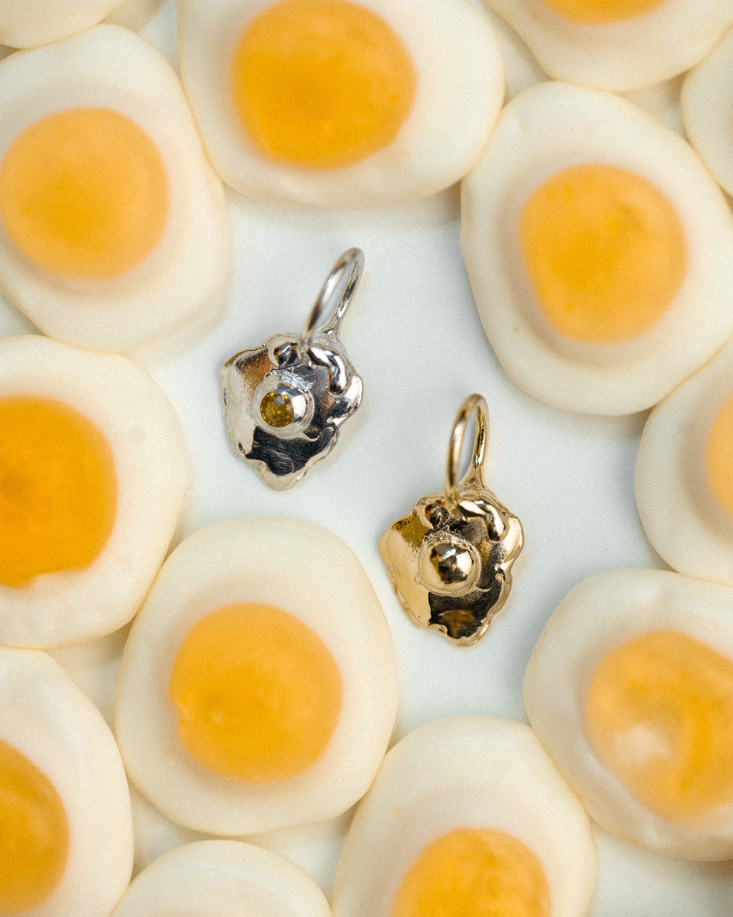 Sunnyside charm in gold and silver surrounded by gummy egg candies